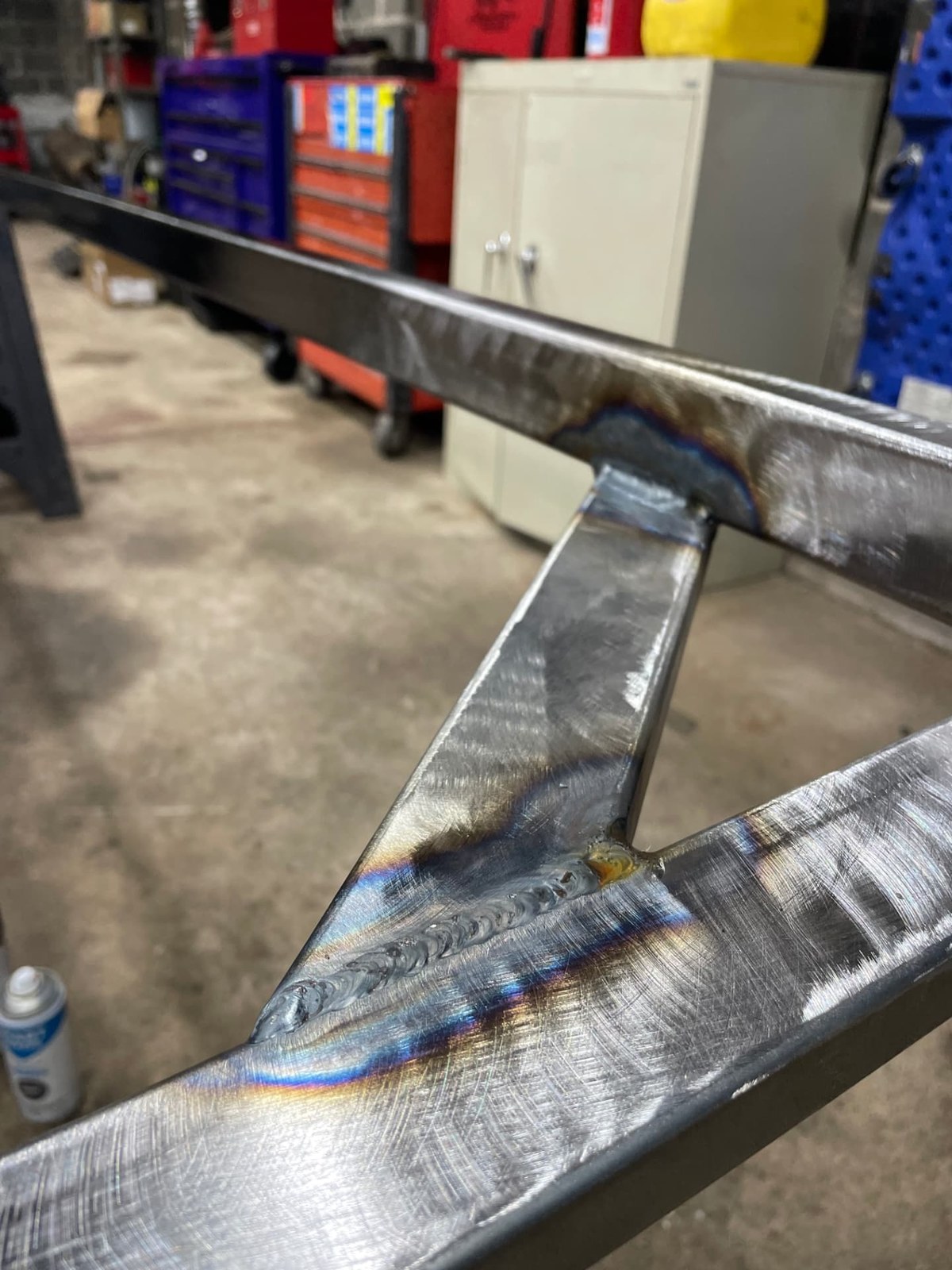 Detailed close-up of a polished weld bead on a steel bracket with heat discoloration