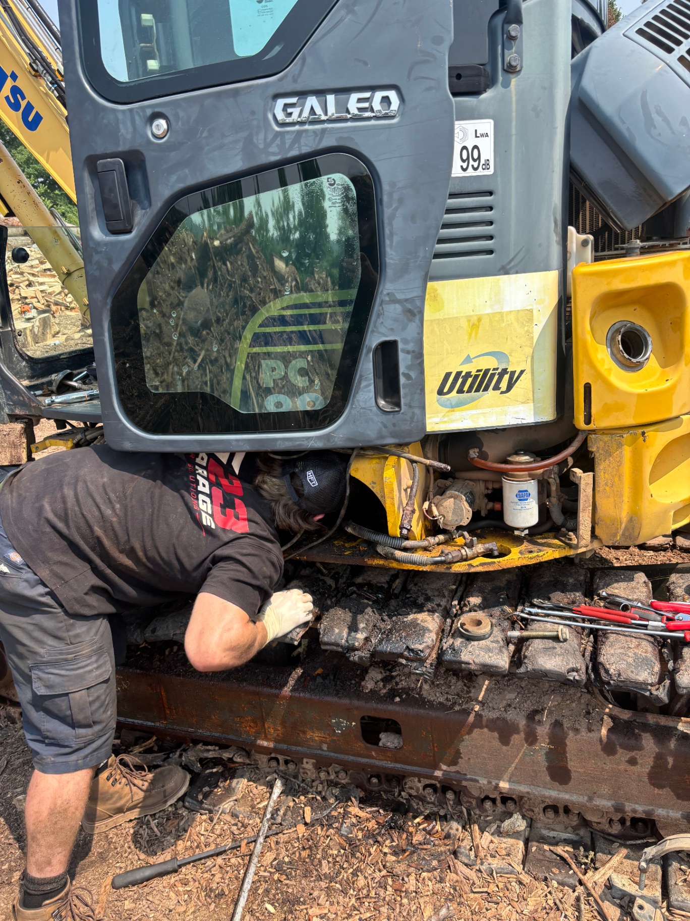 G23 technician servicing the undercarriage track on a Komatsu Galeo mini excavator on-site