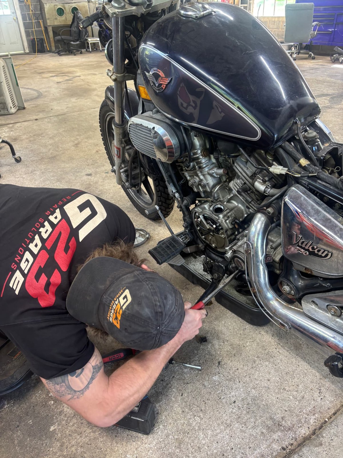 G23 technician draining the oil on a Kawasaki Vulcan 750 motorcycle