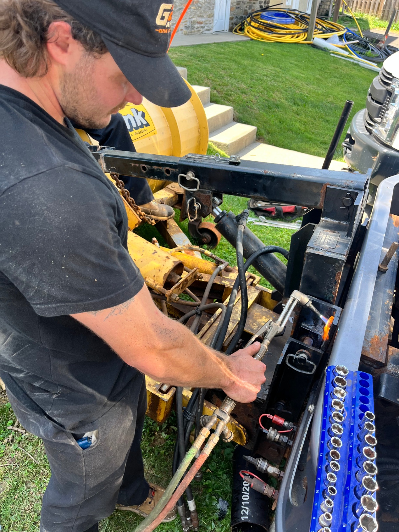 G23 technician using an oxy-acetylene torch to free a seized hydraulic spreader assembly on-site
