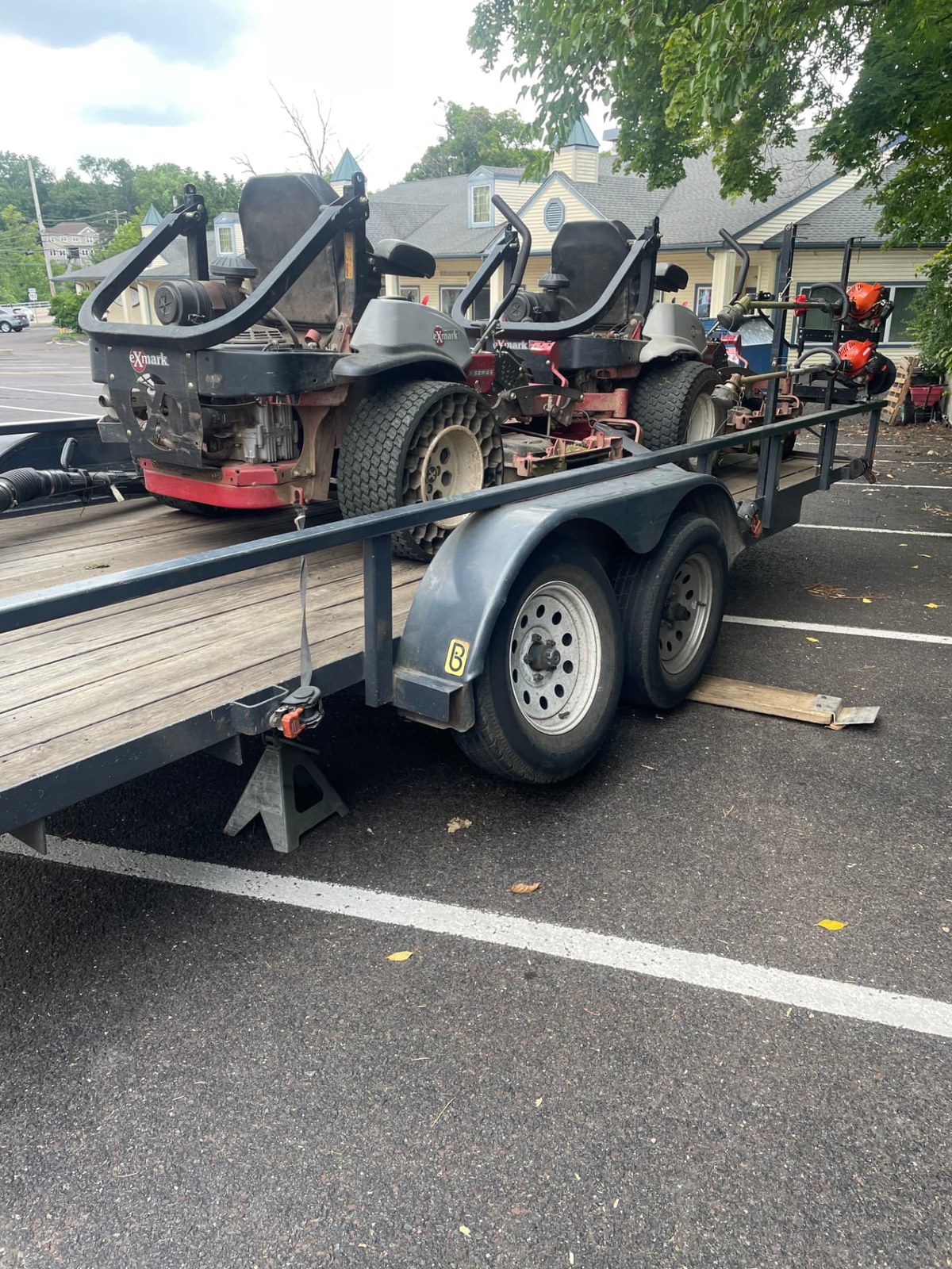 Exmark zero-turn mowers loaded on a flatbed trailer for mobile equipment service