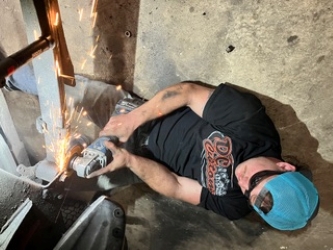 Grinding a fresh weld smooth on an undercarriage repair inside the G23 shop