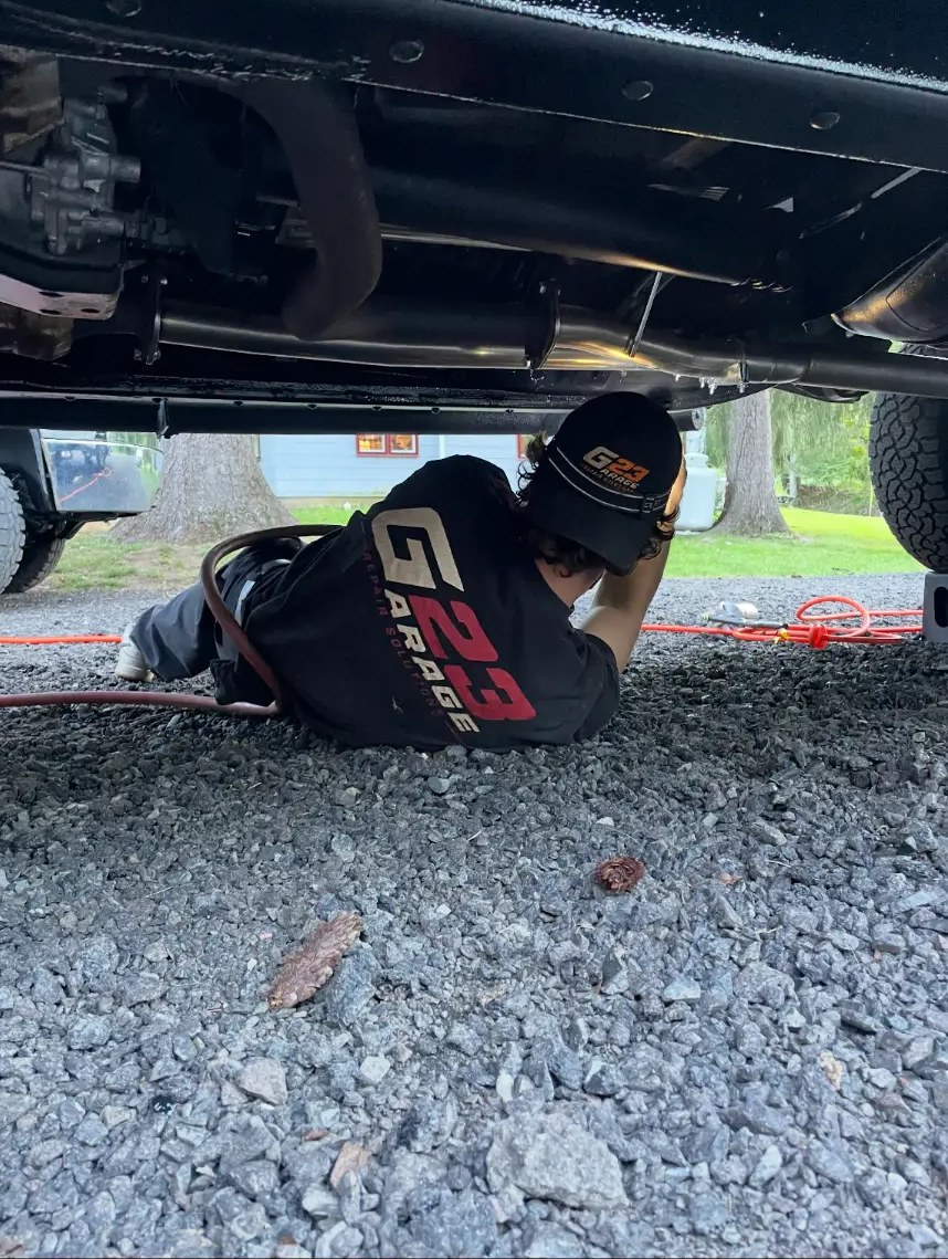 Garage 23 technician inspecting a vehicle undercarriage from below before undercoating